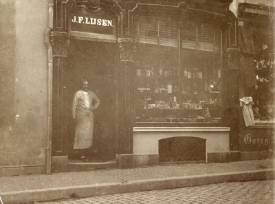 710989 Foto van J.F. Lijsen, brood-, koek- en banketbakker, Potterstraat 23 te Utrecht, in de deuropening van zijn winkel.